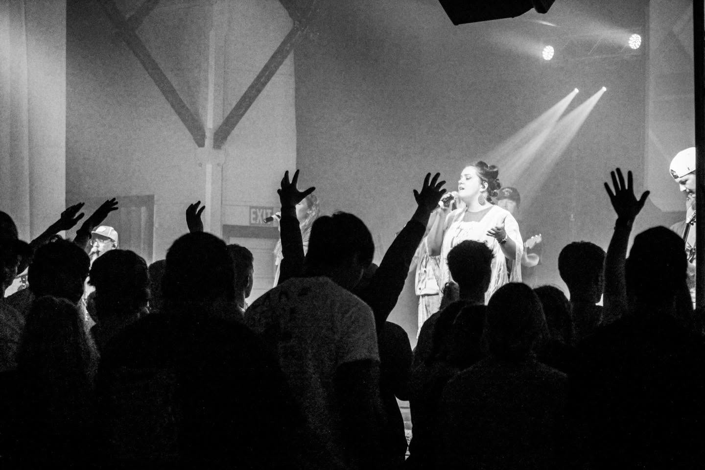 A vocalist leading worship as the congregation raises their hands
